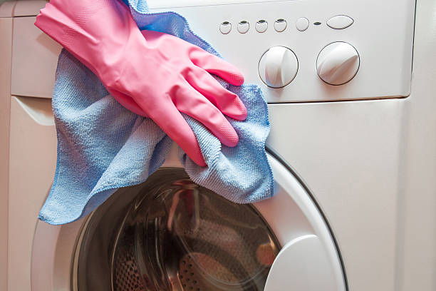 istock Hand in protective glove carefully cleaning the washing machine 626011482