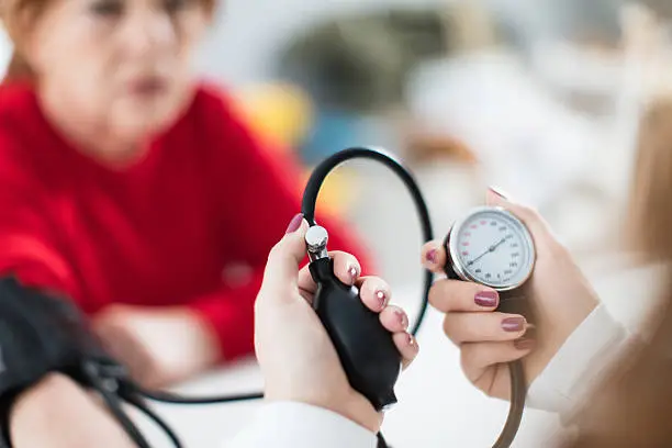 Nurse measuring blood pressure to senior woman