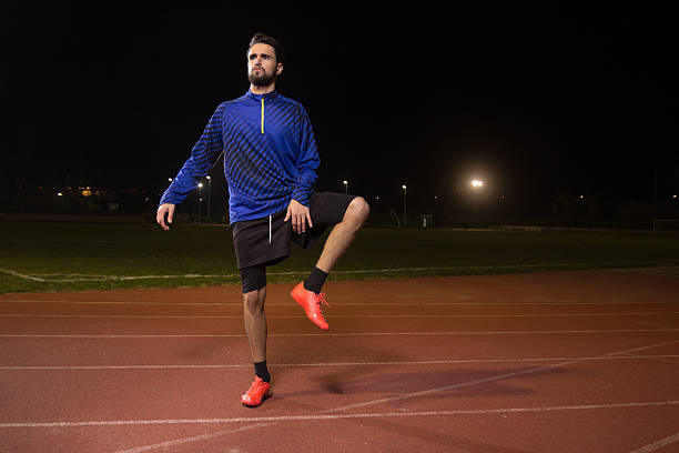 istock Athlete, soccer football player, stetching leg, night dark. 626038656