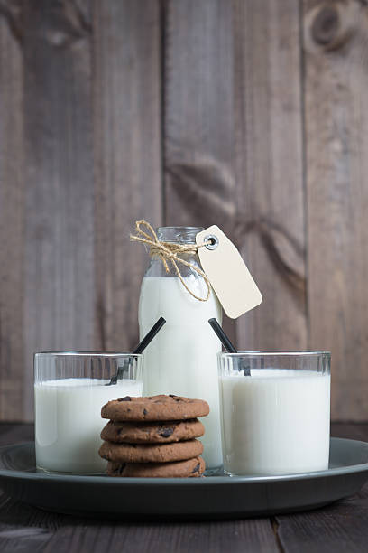 botella de leche con dos galletas transparentes de vidrio y pila - milk milk bottle drinking straw cookie fotografías e imágenes de stock