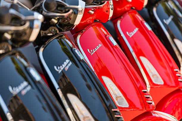 muchos scooters italianos vespa aparcados fuera en la carretera - piaggio fotografías e imágenes de stock