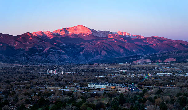 Sunrise on Pikes Peak above Colorado Springs, Colorado The summit of Pikes Peak glows in the morning sunrise as the streets and business office are below the mountain. Garden of the Gods can be seen in the distance colorado springs photos stock pictures, royalty-free photos & images