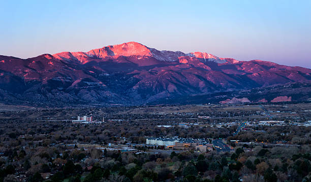 Sunrise on Pikes Peak above Colorado Springs, Colorado The summit of Pikes Peak glows in the morning sunrise as the streets and business office are below the mountain. Garden of the Gods can be seen in the distance colorado springs city stock pictures, royalty-free photos & images