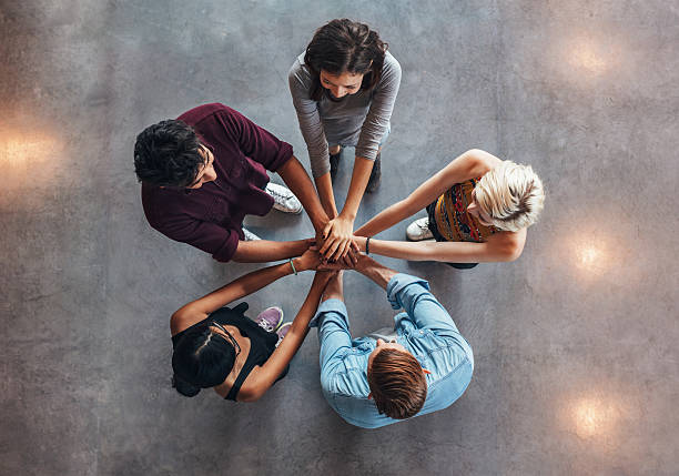 Young people making a stack of hands Young people putting their hands on top of each other symbolizing unity and teamwork. Diverse group of students stacking their hands. stacked hands photos stock pictures, royalty-free photos & images