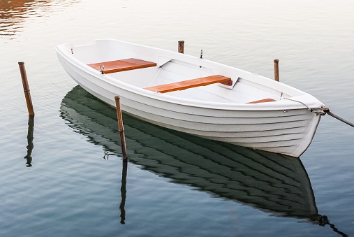 White moored boat on a river with reflection