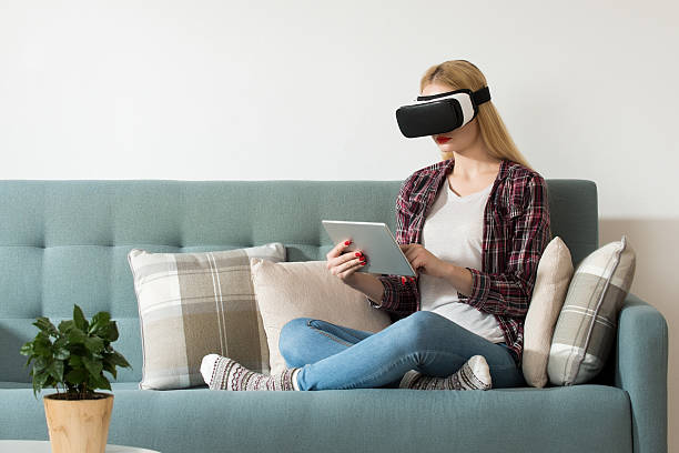 istock Woman wearing virtual reality goggles and sitting on a couch. 626072244