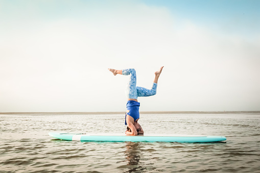 A woman practices yoga on a paddleboard