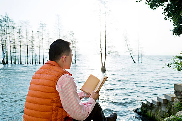 istock Woman reading book by the lake 626073160