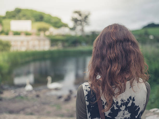 istock Young woman looking at pond 626073478