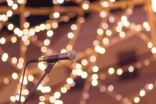 Microphone on stand with smooth soft warm light bokeh background in orange yellow and pink. Concept for live performance, stage, artist, musician, singer, happy times, fun, joy.