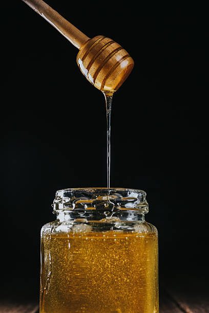 istock Person dipping honey stick in 626087484