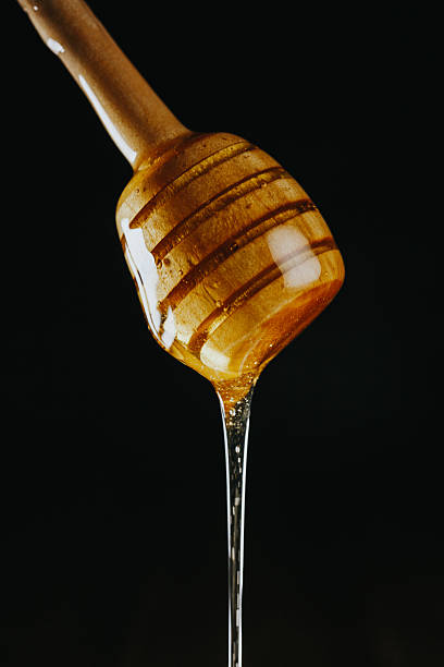 istock Person dipping honey stick in 626087632