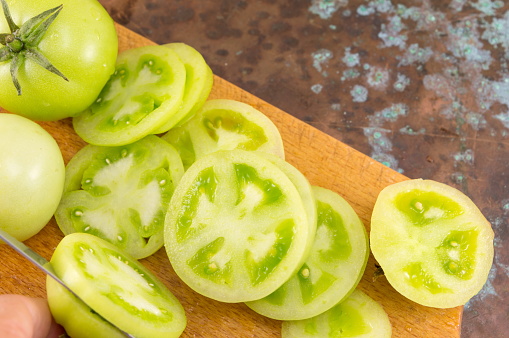 sliced green tomatoes on a wooden cutting board
