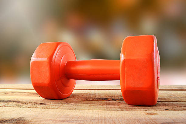 istock Orange dumbbell on wooden. 626099686