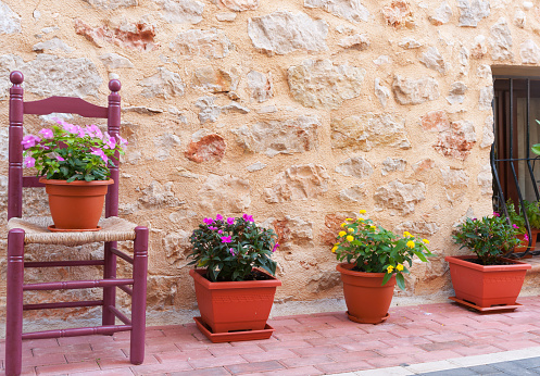 Chair and flower pots decorate home exterior in narrow Spanish traditional village streets