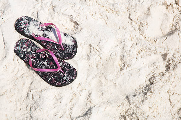 Womans sandals on white sand with free space stock photo