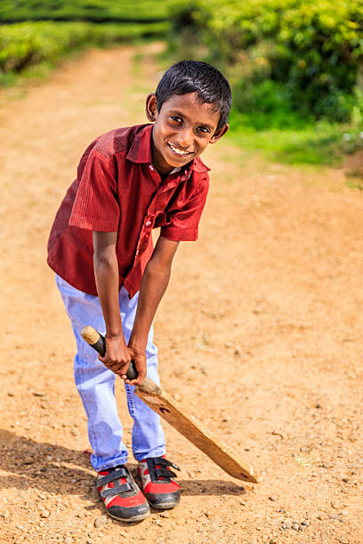 istock Young Sri Lankan boy playing cricket on tea plantation 626133620