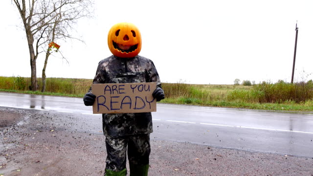 Hitchhiking pumpkinhead man hold sign says Are you ready