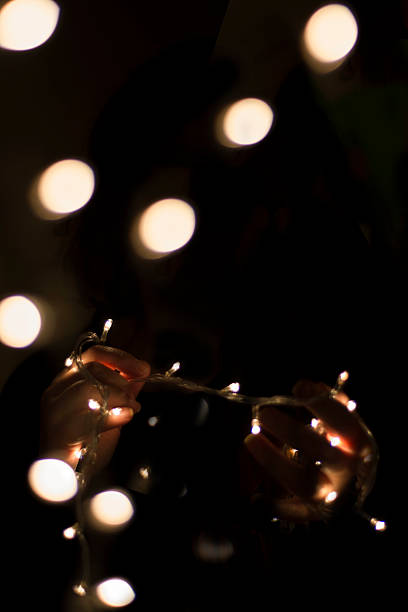 istock Christmas lights in their hands on black background 626177078