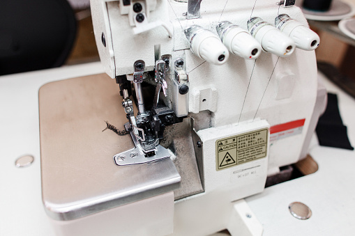 Overlock sewing machine in tailor office close-up. Professional equipment for fashion designer in workshop. Industrial serger