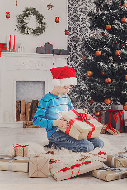 istock Cute happy boy in santa hat unwrapping christmas presents 626186210