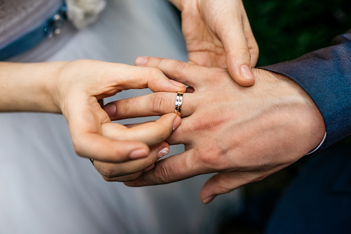 Wedding day. Bride wears the ring on the finger of the groom. Cropped image