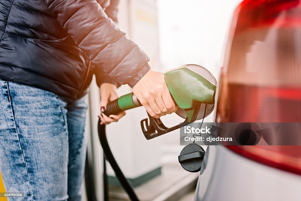Mujer repostando su pequeño coche plateado - Foto de stock de Gasolina libre de derechos