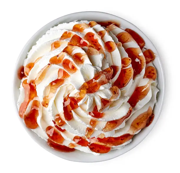 Bowl of whipped cream and strawberry sauce isolated on white background from top view