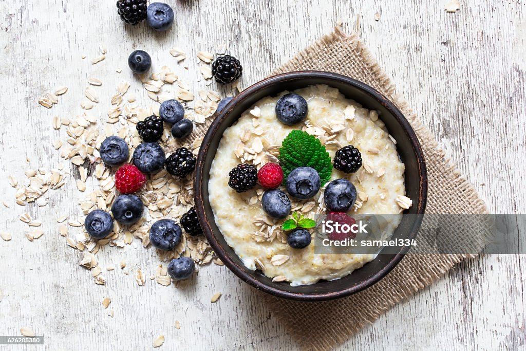 oatmeal porridge with ripe berries oatmeal porridge with ripe berries - blueberry, raspberry and blackberry for healthy breakfast. flat lay. top view Oatmeal Stock Photo