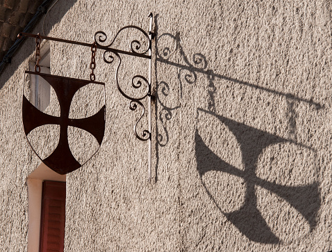 Cathar cross and its shadow in a house of Renne-Le-Château, France.
