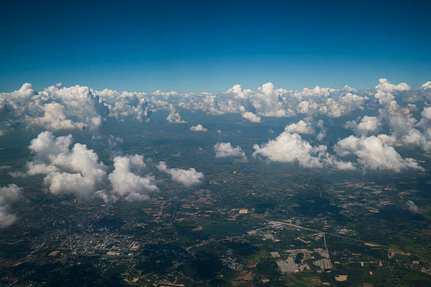 Landscape viewed from airplane Earth landscape viewed from airplane. Earth surface under the white clouds and blue sky from aerial view. Cloudy weather covering residential land and argriculture land. stratosphere airplane cloudscape mountain stock pictures, royalty-free photos & images