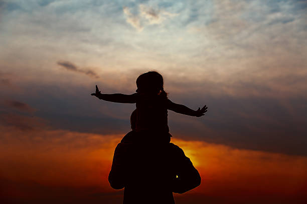 istock Father and little daughter silhouettes at sunset 626217624