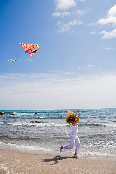 istock Young woman flying kite at the beach 626218362