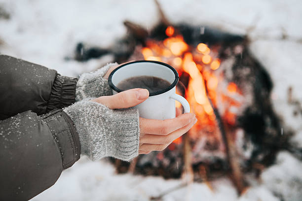 istock Cup of coffee in hands and fire 626225016