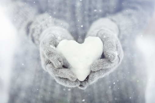 woman holds in her hands a snowy heart