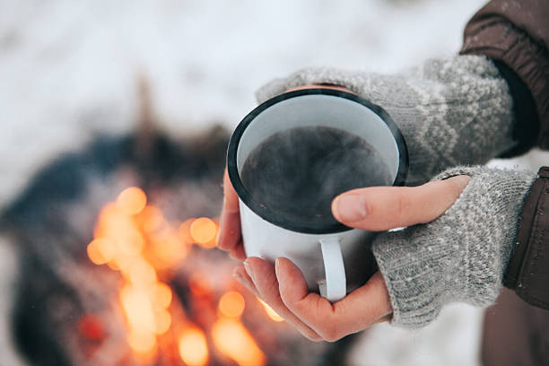 Cup of coffee in hands and fire