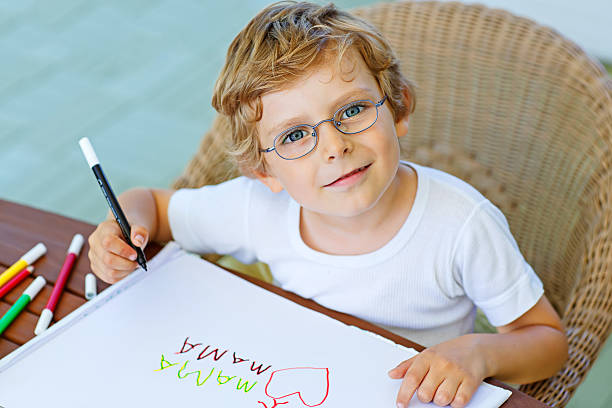 Photo of sweet cute schoolkid doing homework painting with pencil in homemade diy camp have fun on holidays.