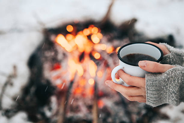istock Cup of coffee in hands and fire 626234340