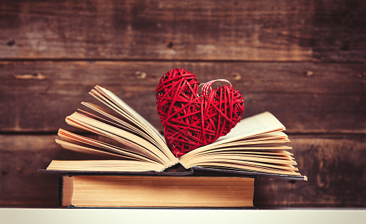 photo of the old books and heart shaped toy on the brown wooden background
