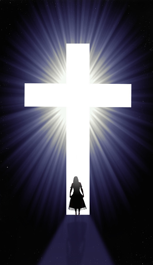 The silhouette of a woman in a dress standing at the foot of a cross of light.