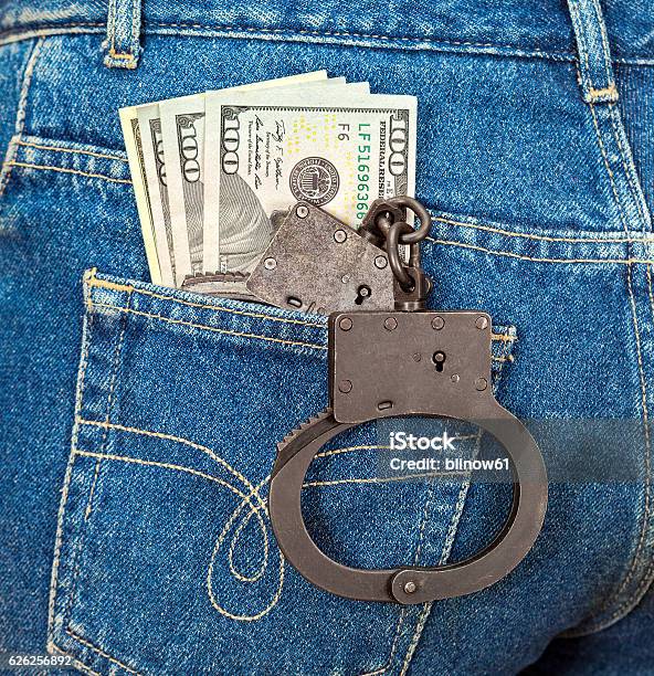 Black Metal Handcuffs And American Currency In Back Jeans Pocket Stock Photo - Download Image Now