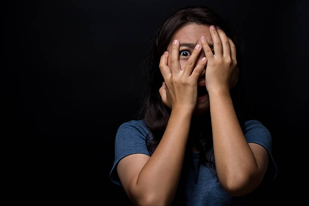 istock Scared woman on isolated black background 626264890