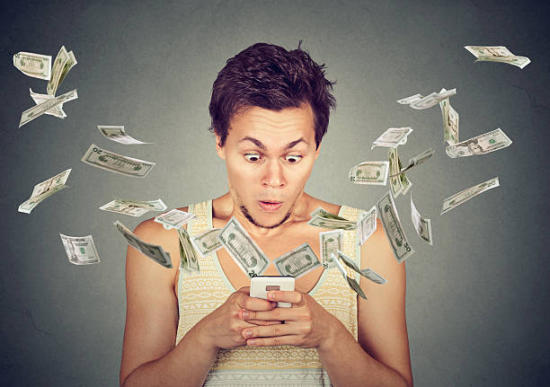 istock surprised man using smartphone dollar bills flying away from screen 626266760