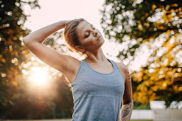 femme de fitness s’échauffant dans le parc - cou humain photos et images de collection