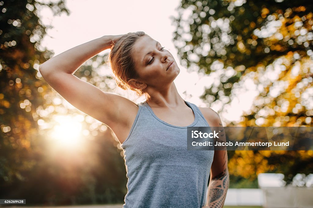 Fitness woman warming up in park Portrait of healthy young woman stretching her neck outdoors. Caucasian fitness model warming up in park. Stretching Stock Photo
