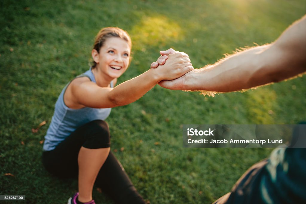 Man helping her girlfriend Man helping her girlfriend with focus on hands. Couple exercising in park. Support Stock Photo