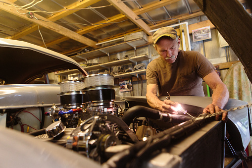 mechanic working in garage shop on antique car