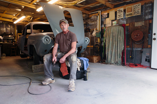 mechanic working in garage shop on antique car