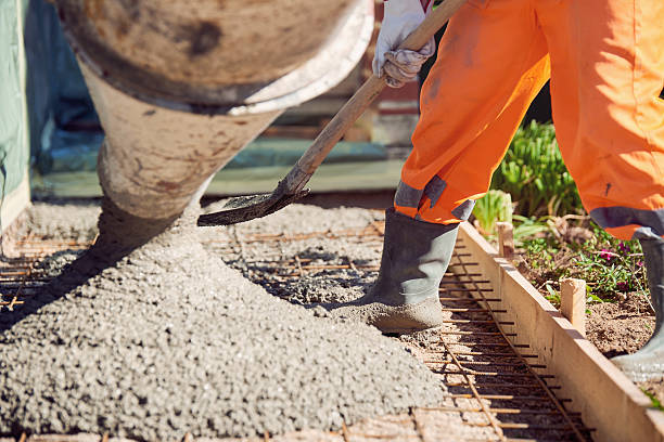 Concrete pouring during commercial concreting floors of building Worker with gum boots spreading ready mix concrete concrete stock pictures, royalty-free photos & images