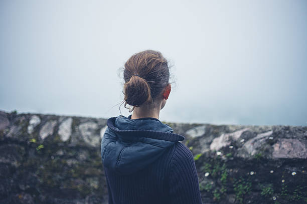 istock Young woman standing by wall in fog 626302500